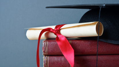 graduation cap, diploma, and old books